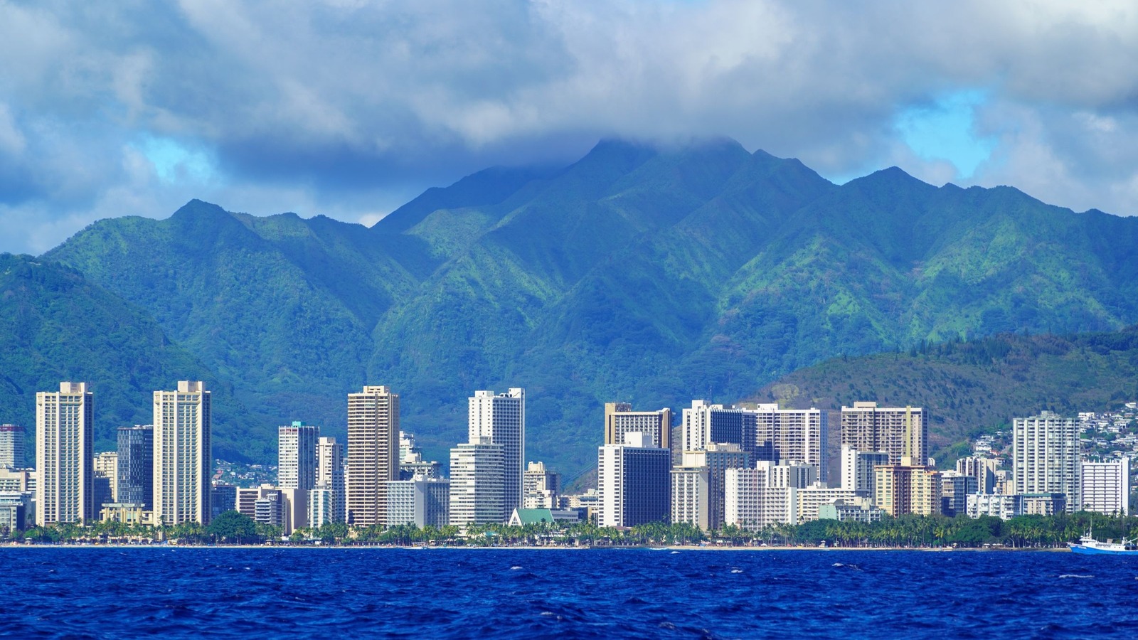 Honolulu waterfront skyline with green mountains behind it